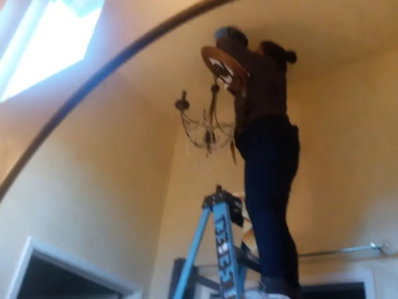 Electrician installing a chandelier in a Somerville residence